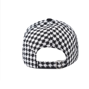 Detail of black and white houndstooth cap with adjustable silver metal buckle back