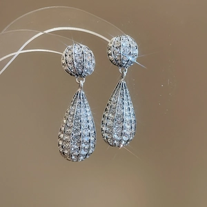 Macro shot of silver drop earrings with sparkling pavé rhinestones in a luxury jewelry style