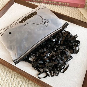 Macro view of high-elastic black hair ties in a frosted pouch with cartoon duck graphics