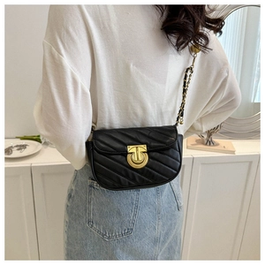 Detail of black V-quilted crossbody bag with gold chain strap on a female model