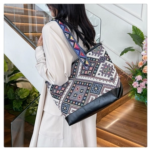 Detailed side view of multi-color geometric ethnic canvas tote bag with wide strap