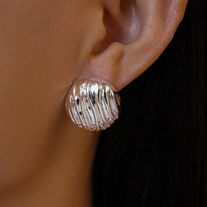 Gros plan d'une boucle d'oreille argentée ronde texturée portée par un mannequin pro