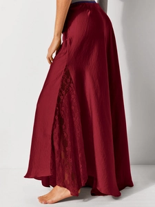 Detail of elegant burgundy satin skirt featuring delicate lace patchwork and side slit