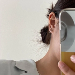 Close-up of minimalist 925 sterling silver ball stud and decorative bar earring on ear