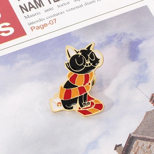 Macro shot of an enamel black cat pin wearing a scarf and glasses on a white envelope