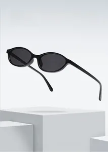 Detail view of oval black frame sunglasses resting on white geometric blocks