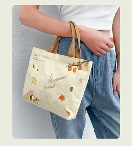 Close-up of autumn harvest illustrations on a cream canvas tote bag with brown handles