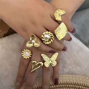 Detail of 7pcs gold pearl ring set with butterfly heart and flower motifs on hand
