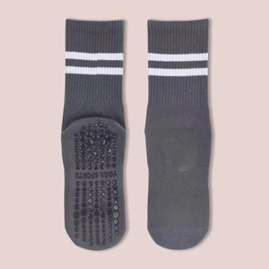Detail of grey yoga socks with white stripes and black anti-slip grips on the bottom