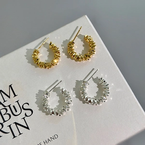 Unregelmäßige C-förmige Ohrringe in Gold und Silber mit strukturierter geometrischer Textur