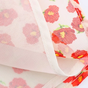 Detailopname van bloemige chiffonstof met rode en gele patronen en netjes afgewerkte naden