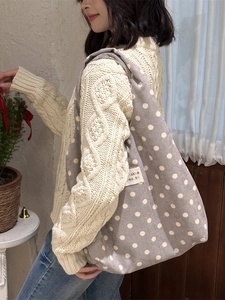Grey corduroy tote bag with white polka dots and zakka beauté label on a model