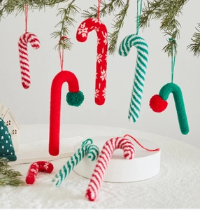 Close-up of knitted candy cane ornaments on pine branches for Christmas tree decor
