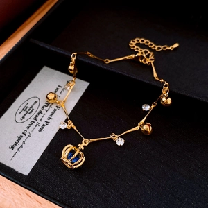Détail du bracelet couronne doré avec gemme bleue sur une boîte à bijoux en velours