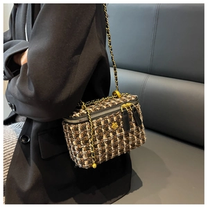 Détail du sac bandoulière en tweed avec badge camélia doré et bandoulière chaîne