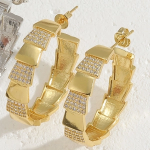 Macro shot of gold C-shaped hoop earrings with pave-set zircon snake scale pattern