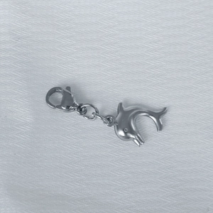 Polished silver stainless steel dolphin pendant with lobster clasp on white fabric