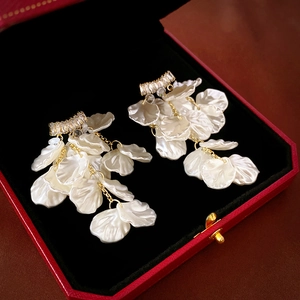 Détail des boucles d'oreilles fleur en nacre avec pampilles en zircon sur velours noir