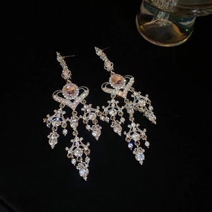 Close-up of sparkling tassel earrings with pink gems and crystals on black velvet