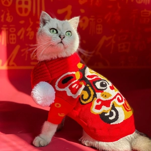 Detail of red knitted pet sweater featuring traditional lion dance pattern and plush pom-poms