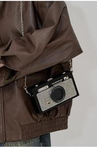 Close-up of camera-shaped crossbody bag with sparkling silver rhinestones and chain strap