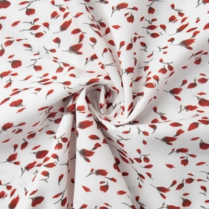 Détail de la texture du tissu floral avec imprimé pétales rouges sur coton blanc