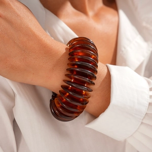 Macro detail of amber resin chunky bangle with spiral texture on model's wrist