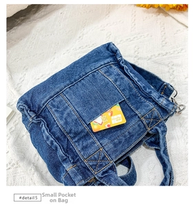Close-up of vintage blue denim shoulder bag with front pocket on white lace background