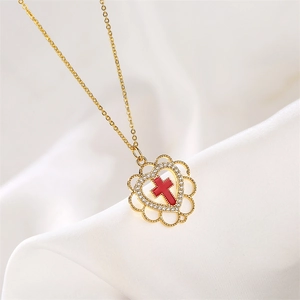 Close-up of gold heart pendant with red cross and micro-set zircons on white silk