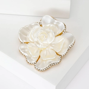 Elegant white pearlized flower brooch with gold edges and crystals on geometric stands