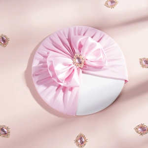 Close-up of pink baby turban with a large satin bow and central rhinestone detail