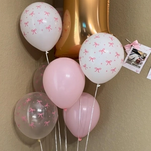 Close-up of pink and white latex balloons with bow patterns for newborn party decor
