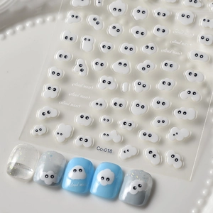 Detail of 3D embossed white cloud nail stickers with cute faces on blue manicured nails