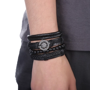 Détail de bracelets multicouches en cuir tressé pour hommes avec un charme de boussole