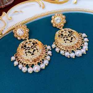 Detailed close-up of vintage hollow gold earrings with sparkling rhinestones and pearl tassels