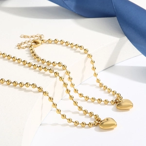 Vue détaillée du pendentif cœur en plaqué or 18K sur un collier de perles chic