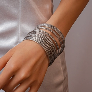Dettaglio di 20 bracciali rigidi argento sovrapposti con finitura lucida e texture