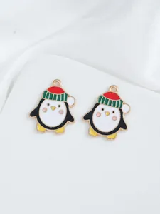 Close-up of DIY Christmas penguin charms with red hats and gold edges on white silk
