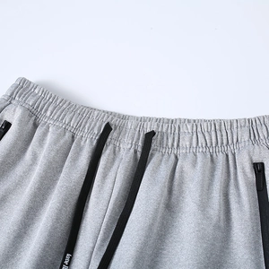 Detalle de cintura de pantalón deportivo gris para hombre con cordón y bolsillo con cremallera