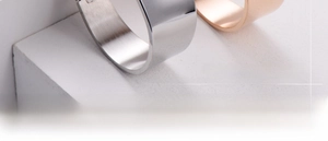 Polished silver and rose gold metal bangles displayed on white geometric stones