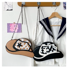 Detail of cow-print cowboy hat-shaped crossbody bags with star accents and chain straps