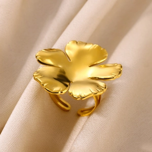 Close-up of golden vintage flower ring on beige silk background showing floral details