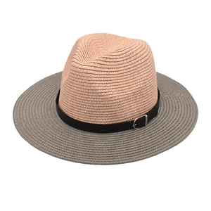 Détail du chapeau de paille bicolore montrant le tissage dense et la boucle de ceinture noire