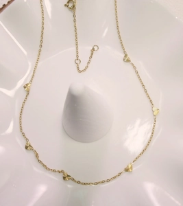 Close-up of golden O-chain necklace featuring multiple laser-cut heart pendants with radial patterns