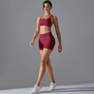 Detail of burgundy high-waisted shorts and cross-back sports bra on a model fitness set