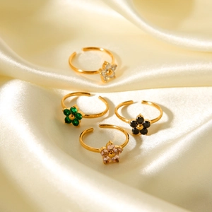Detailed view of four colorful flower-shaped zircon rings on elegant beige satin fabric