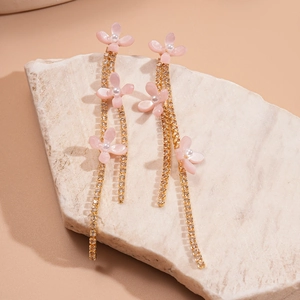 Close-up of pink resin flower earrings with gold tassel chains and white pearls
