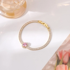 Close-up of gold bracelet featuring a pink round zircon surrounded by white crystals