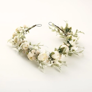 Dettaglio della corona di fiori da sposa fatta a mano bianco crema con foglie verdi