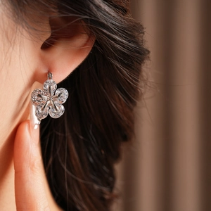 Gros plan de boucles d'oreilles fleurs en zircon portées par un mannequin en argent